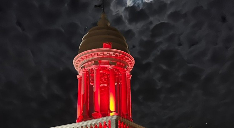 La luce rossa della speranza riflette sulla Torre dell’Orologio
